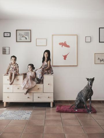 Retrato de Familia de las niñas Mae, Naru y Umi sobre un mueble con la galga Sofía sobre una cama de perro.